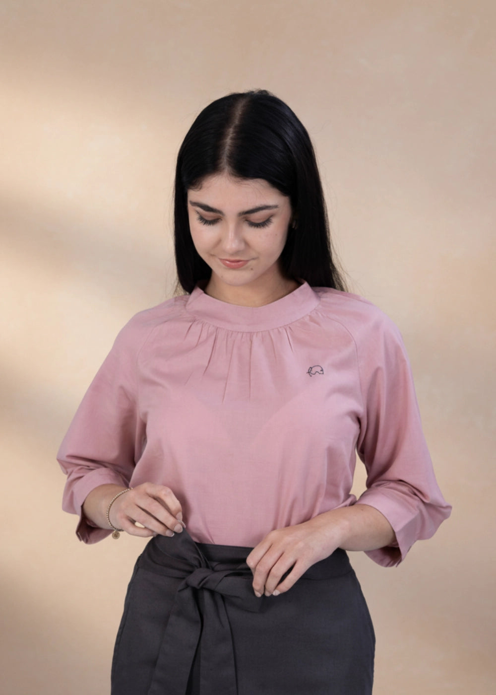 Woman wearing flamingo rose 3/4 sleeve linen–cotton top with mock neck.