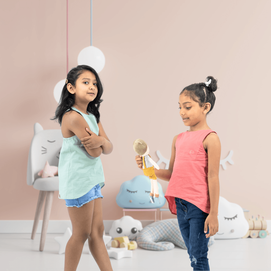 Two young girls standing in a pink room.