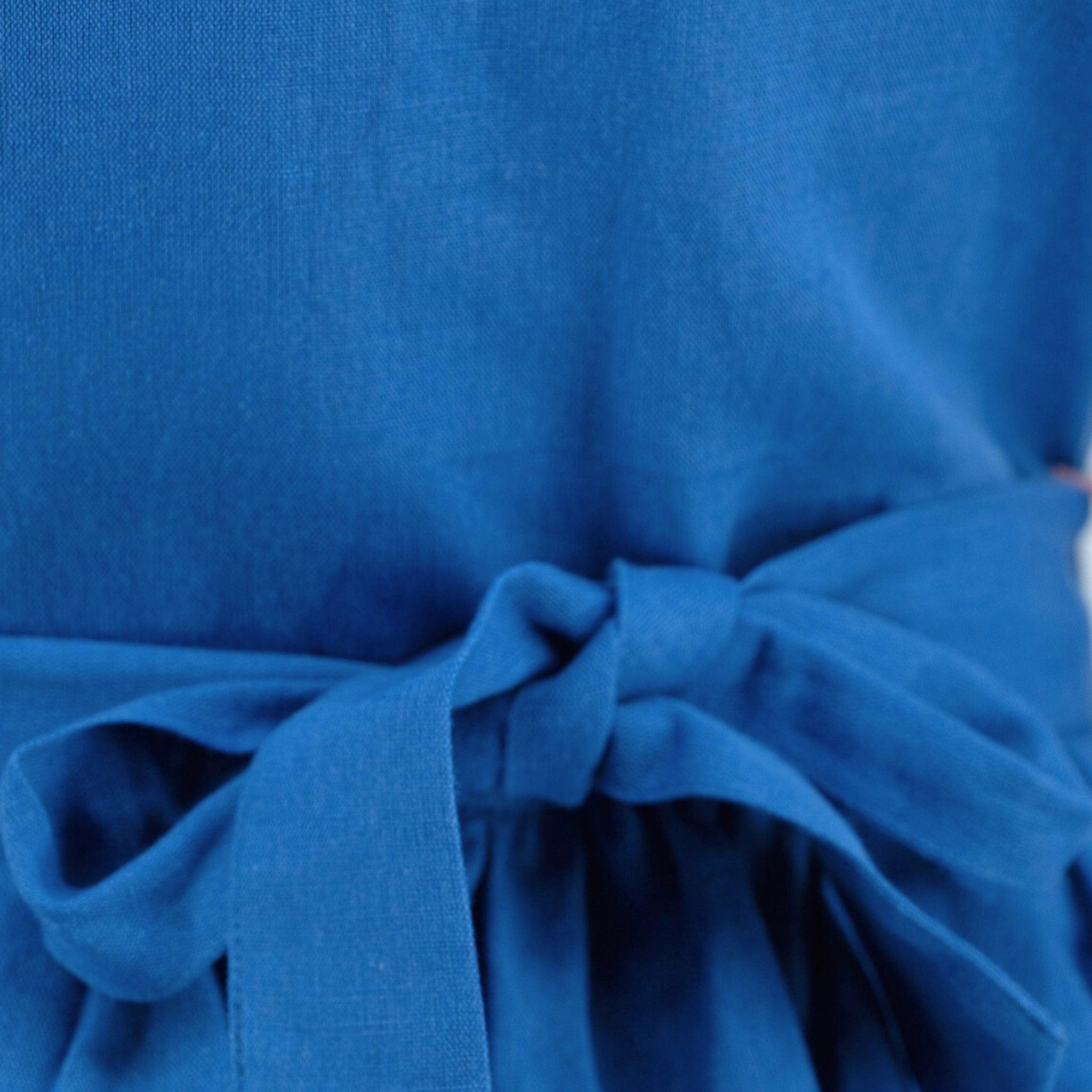 Close-up of a Karee Parisian Blue Linen Dress for Girls with a bow detail, focusing on the texture and folds of the material.