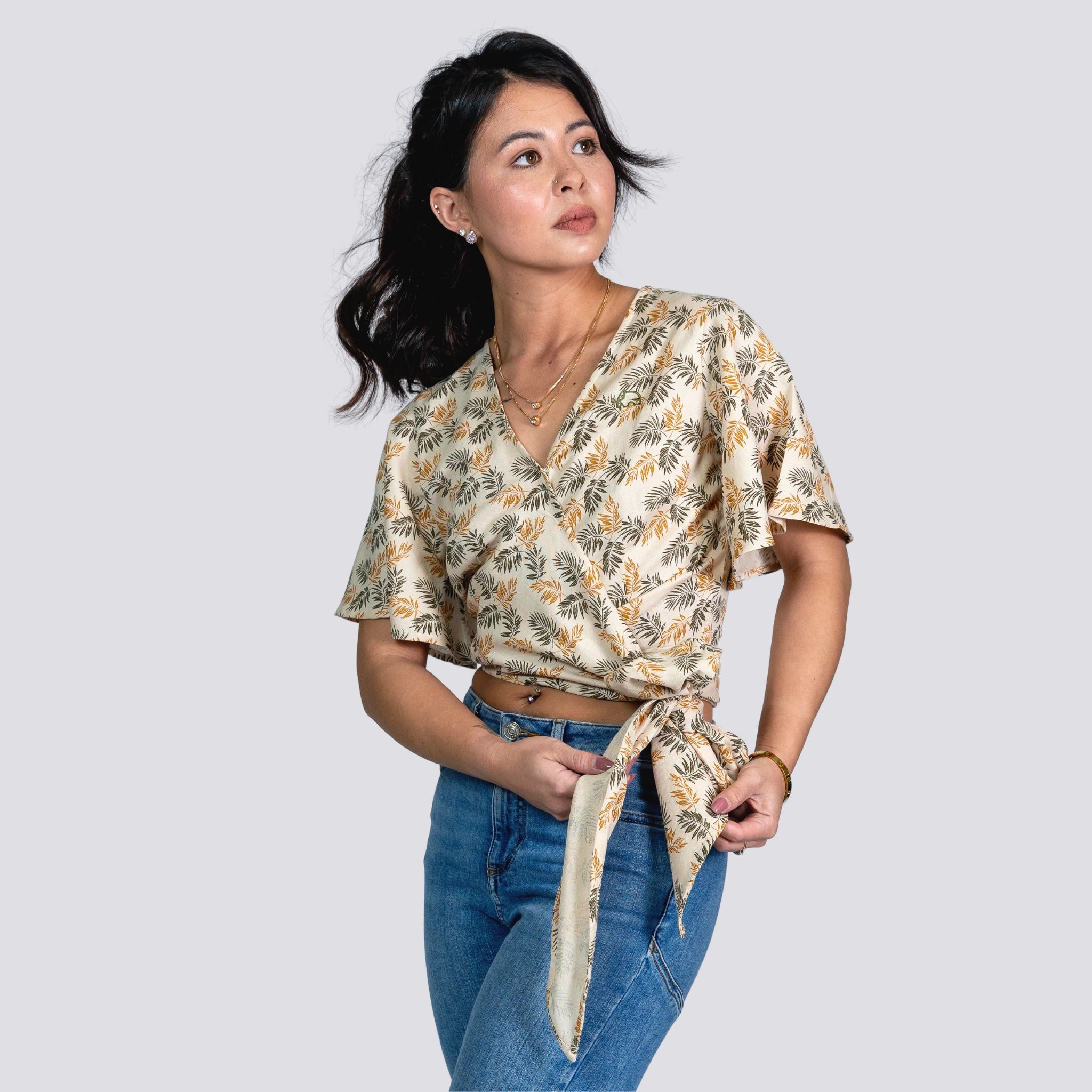 Woman in a ChicPalms Women's Eco-Friendly Wrap Top - Biscuit Bliss by Karee and jeans looking to the side against a gray background.