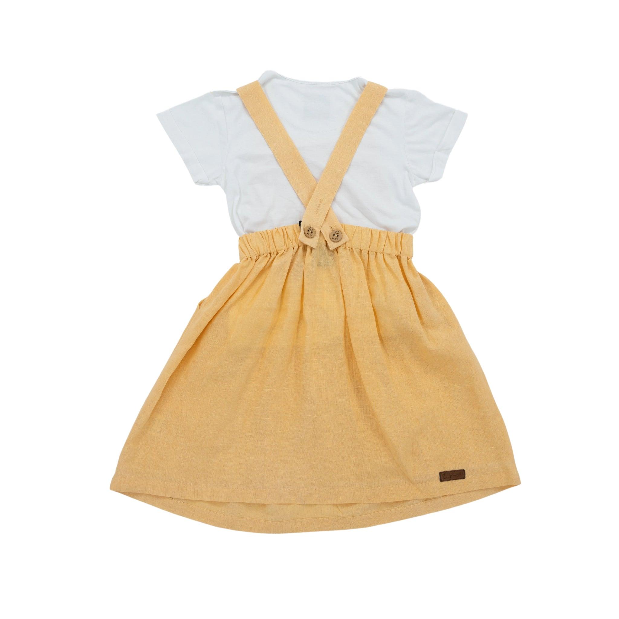 Child's outfit consisting of a white shirt and a Golden Fleece Linen Pinafore suspender skirt made from sustainable linen cotton, on a white background by Karee.