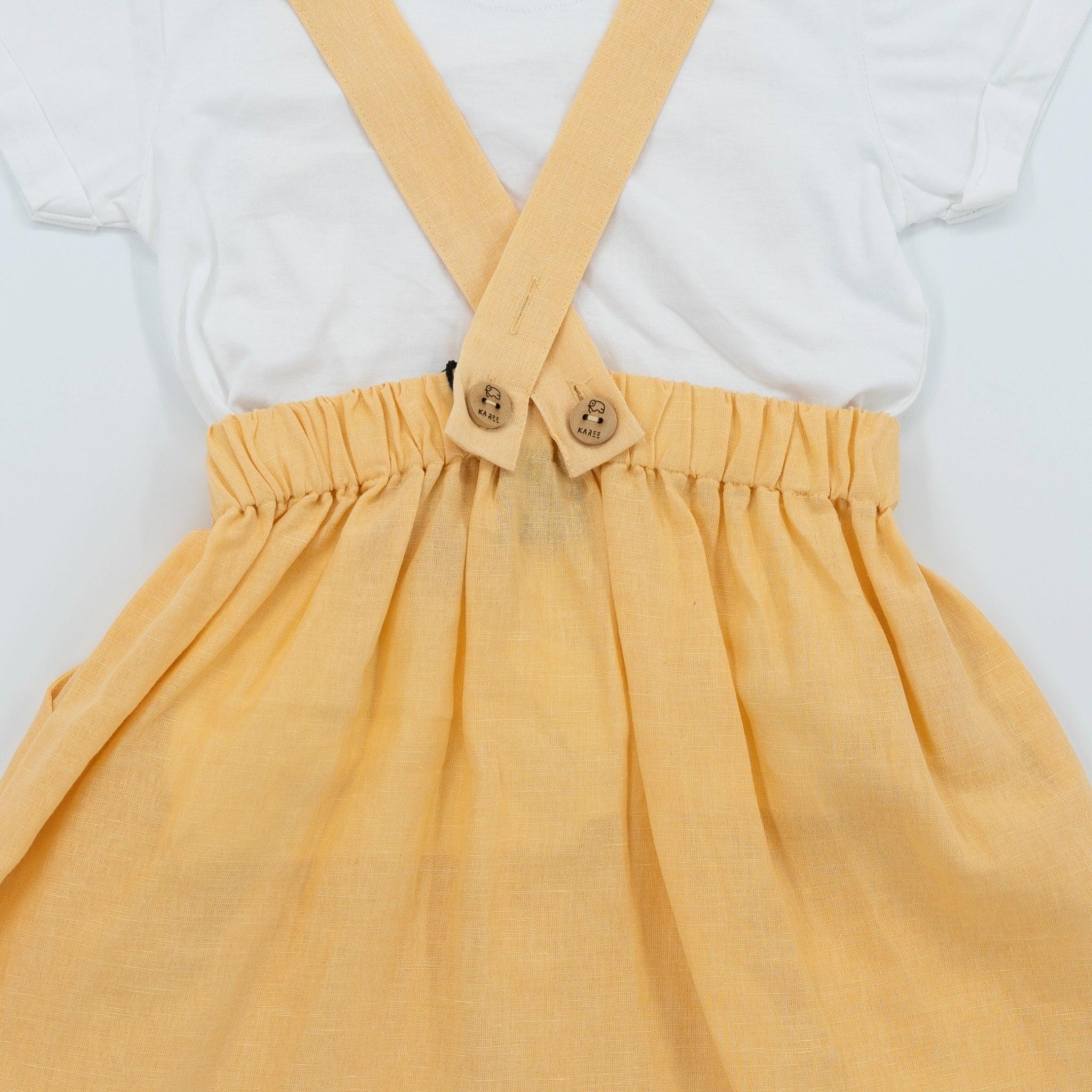 Close-up of a child's outfit with a white t-shirt and Golden Fleece Linen Pinafore made from premium linen cotton, displayed against a white background by Karee.