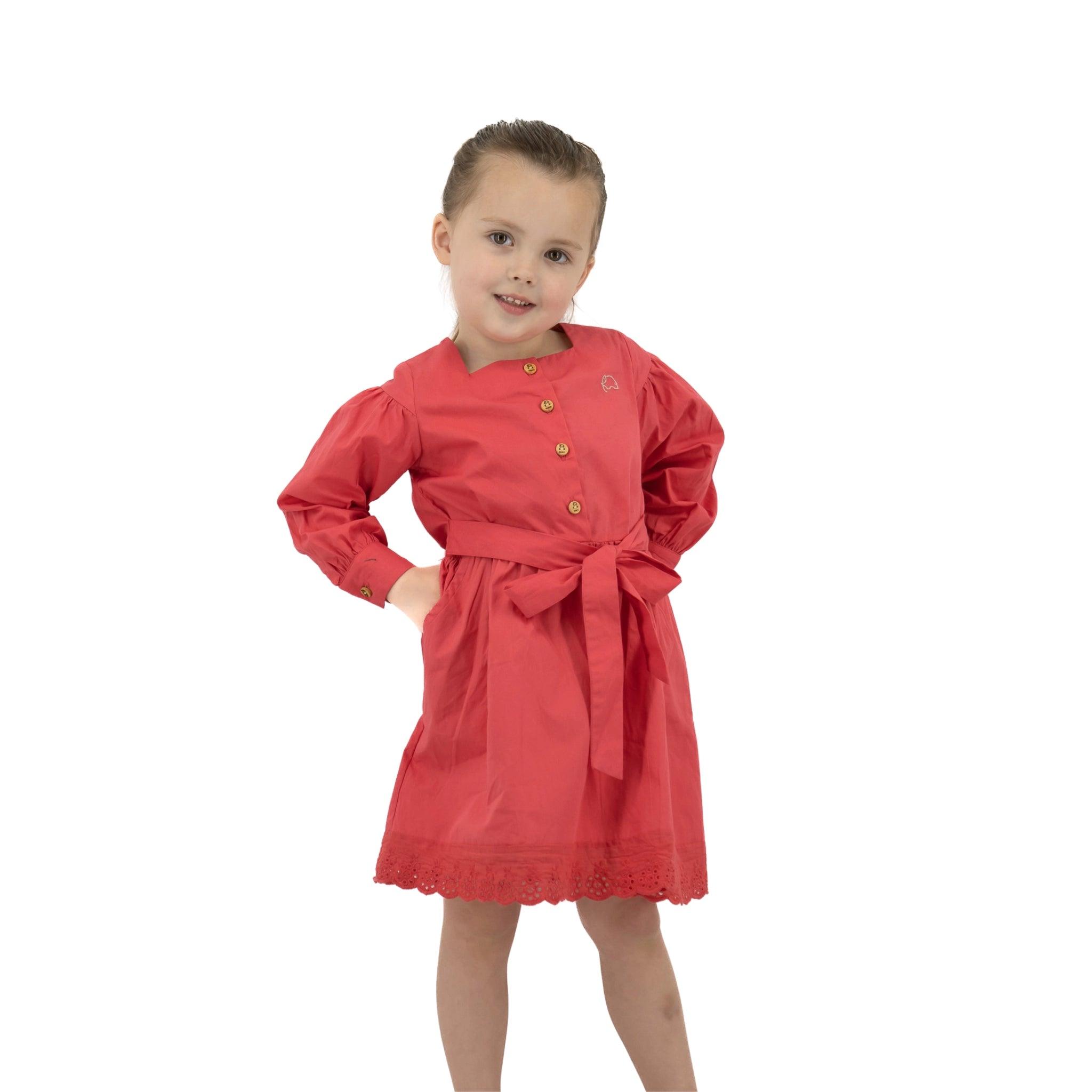 Young girl in a Karee red long puff sleeve cotton dress posing with hands on hips, standing against a white background.