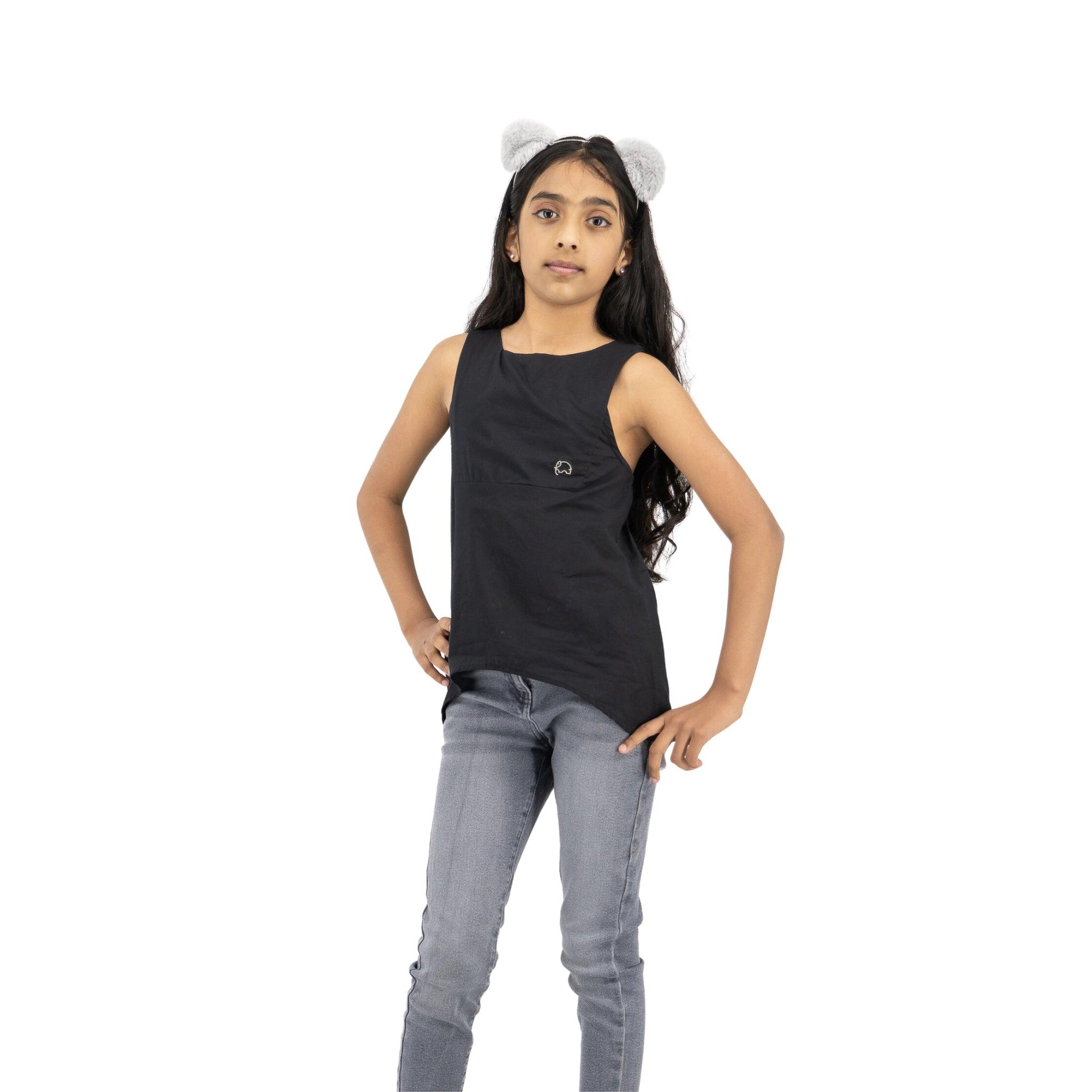Young girl wearing a Karee Black Beauty Cotton Bib Neck Top for kids and blue jeans, hands on hips, looking to the side, isolated on a white background.