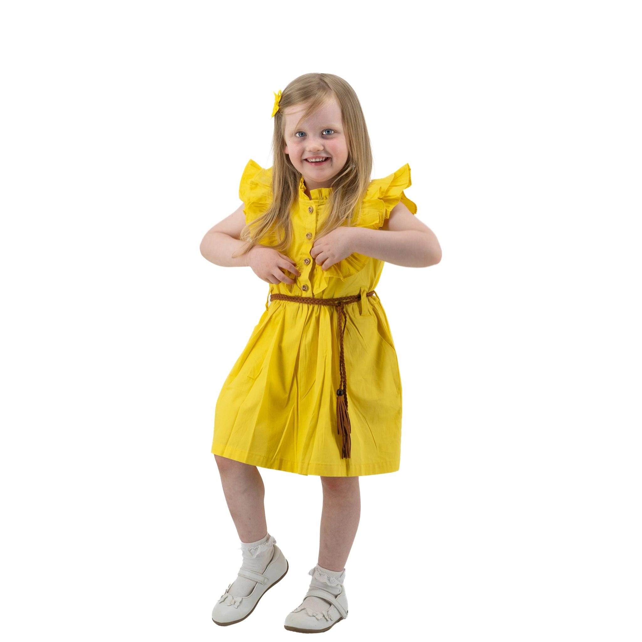 Young girl in a Karee yellow butterfly sleeve cotton dress for girls smiling and standing against a white background.