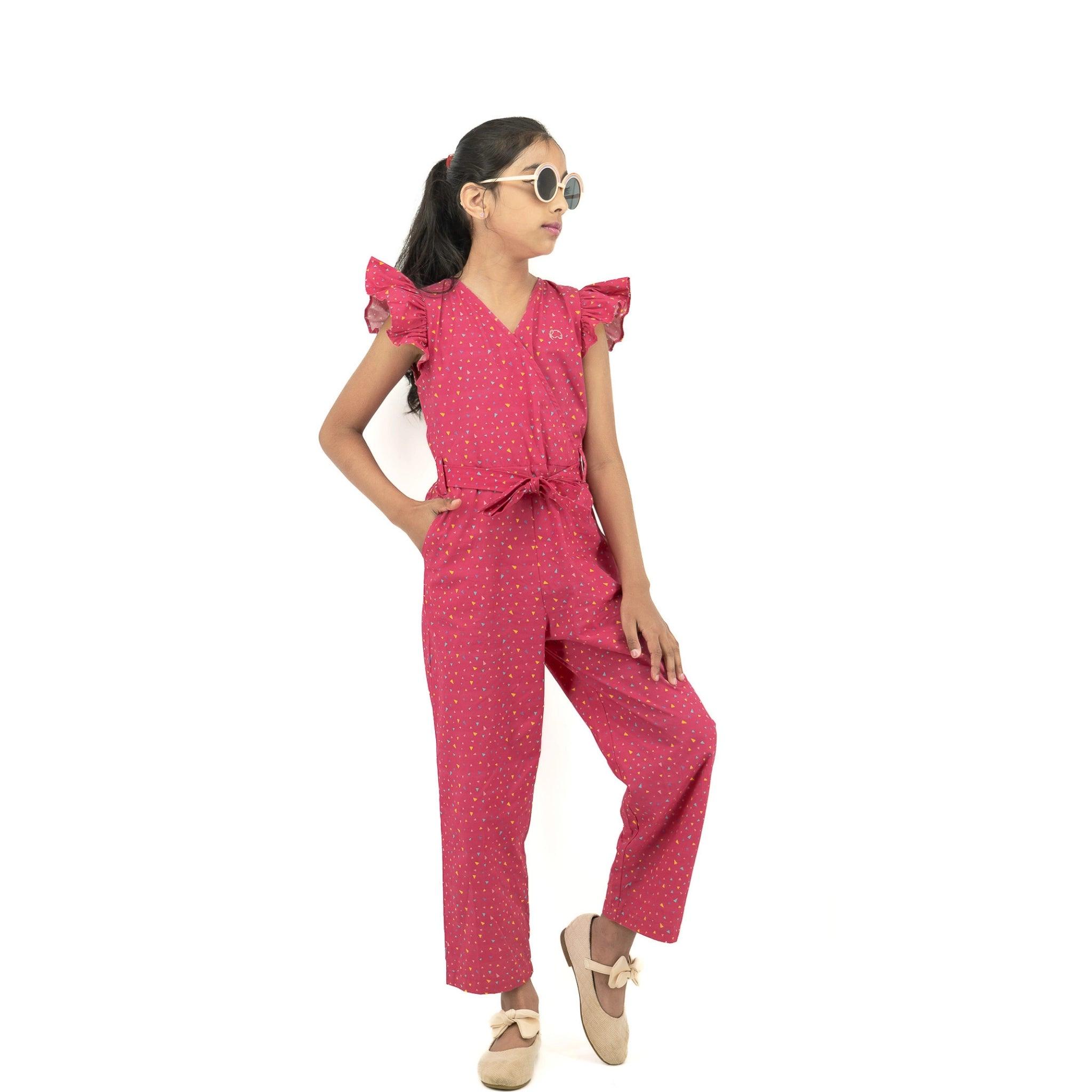 Young girl in a Red Rose cotton jumpsuit for girls by Karee and sunglasses, posing confidently with one hand on her hip, against a white background.