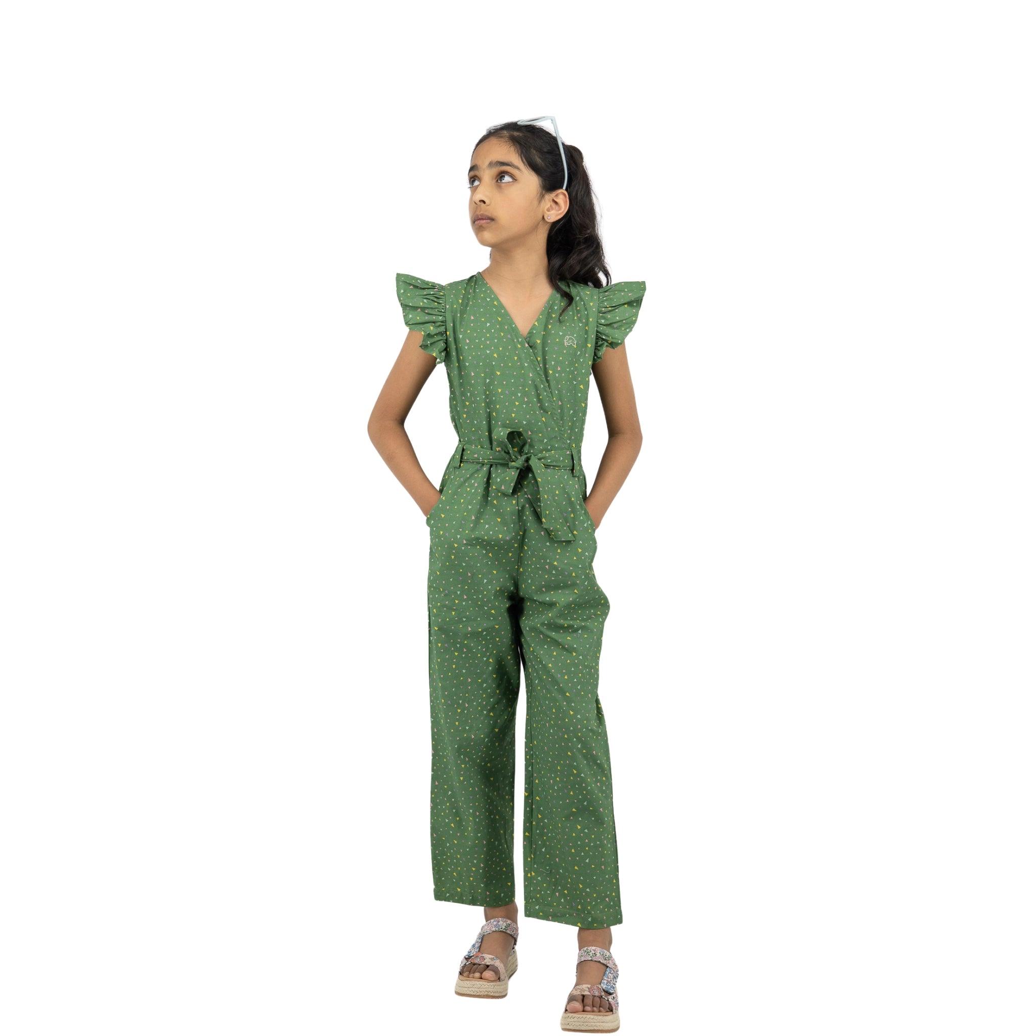 Young girl in a Karee Green Confetti Cotton V-Neck Jumpsuit for Kids with ruffled sleeves, standing and looking to her left, isolated on a white background.