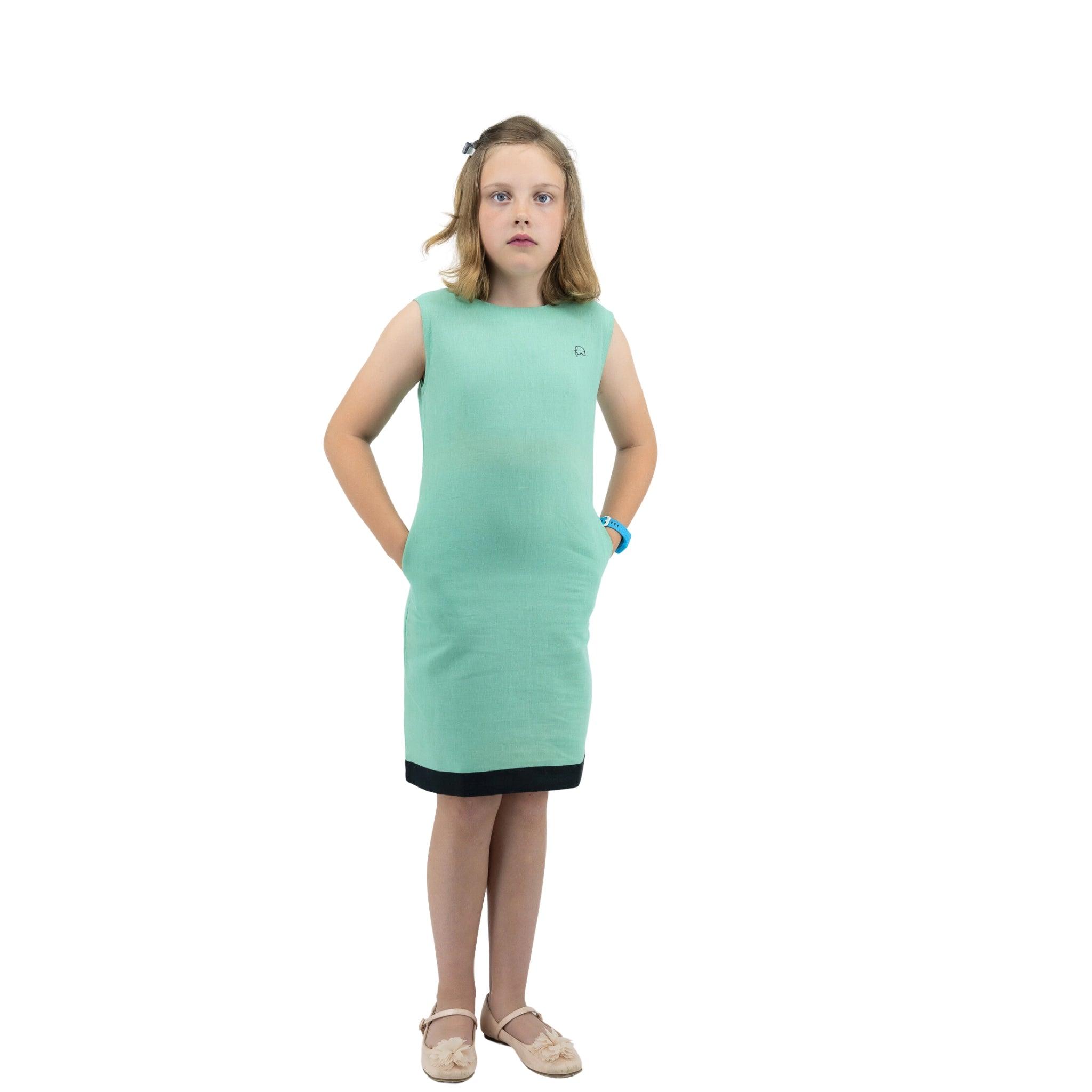 Young girl in a Karee Neptune Green Linen Cotton Round Neck Frock standing with hands on hips against a white background.