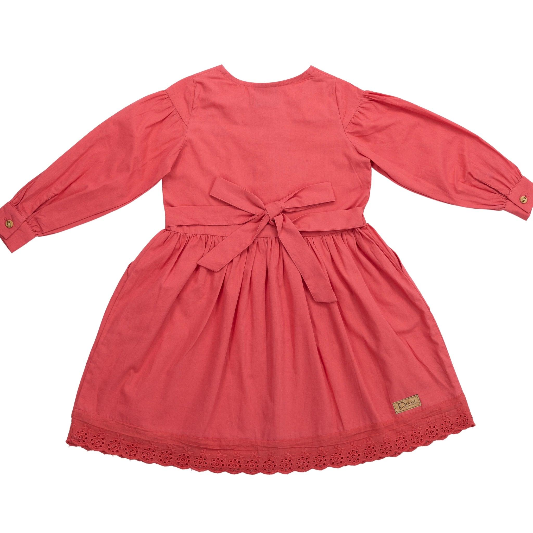 A coral pink toddler's dress with long puff sleeves, a bow at the waist, and lace trim along the hem, displayed flat on a white background.
