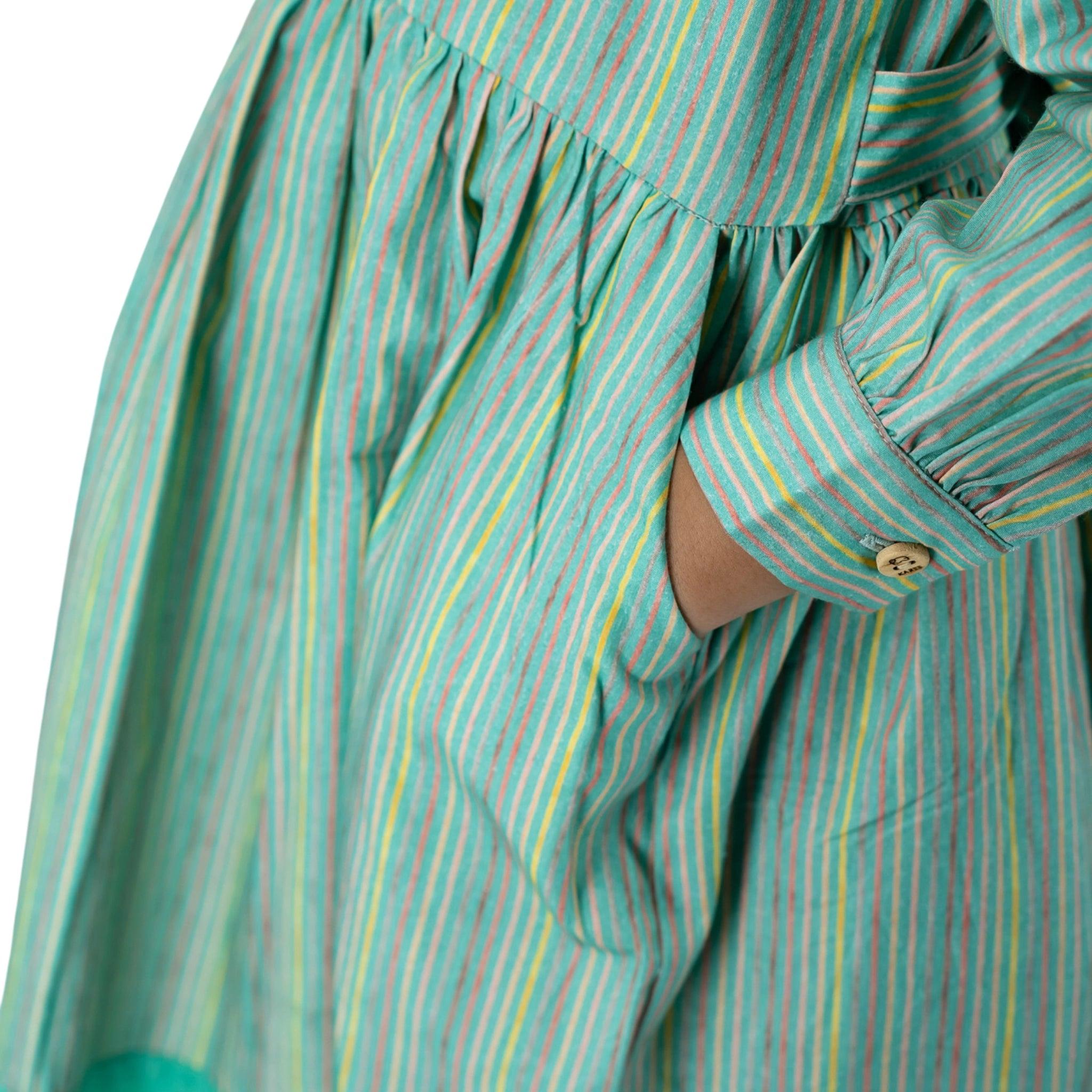 Close-up of a person wearing a Karee Green Striped Long Puff Sleeve Cotton Dress with a Karee wooden button on the cuff.