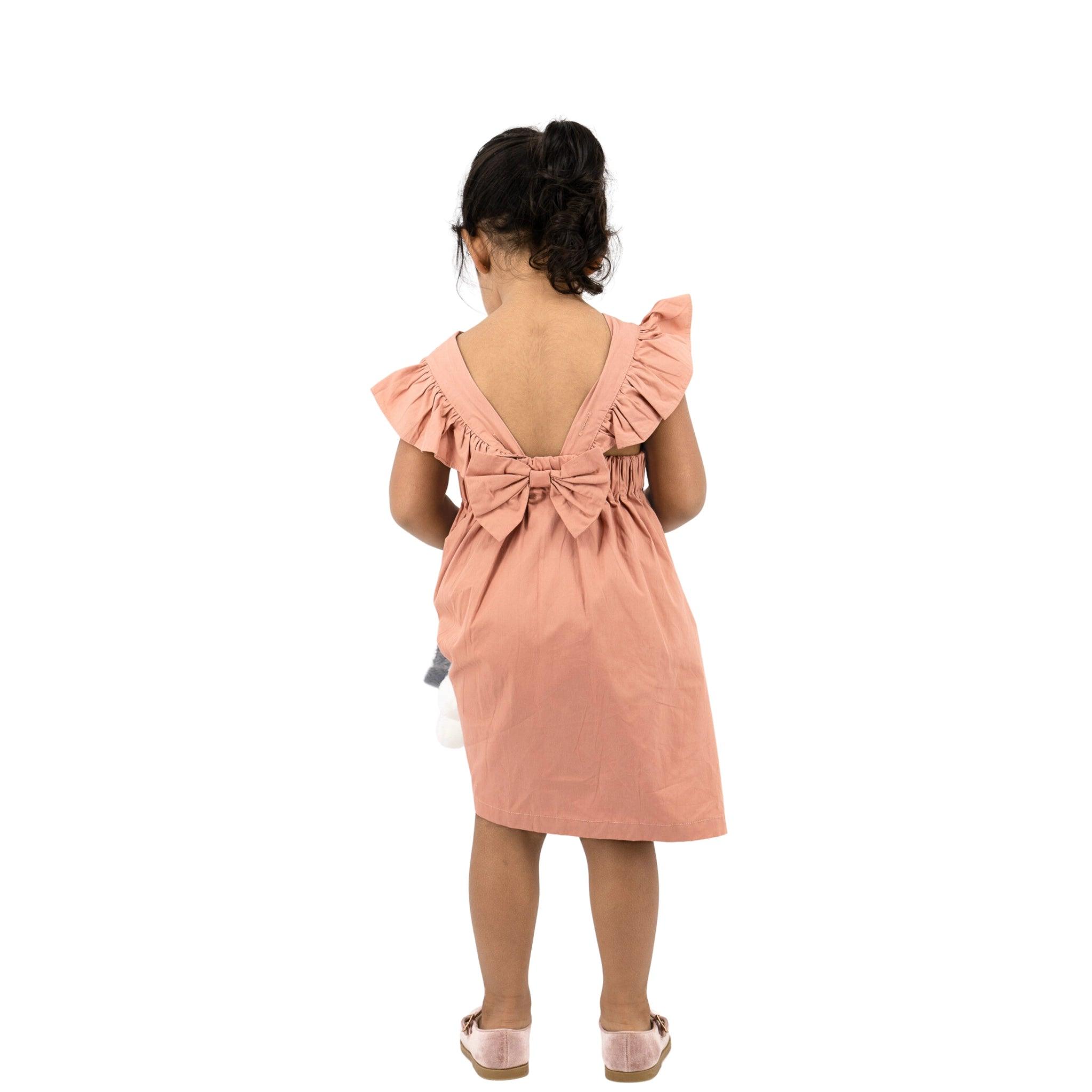Young girl in a Brick Dust Cotton Floral Dress for Girls by Karee, seen from behind, standing against a white background.