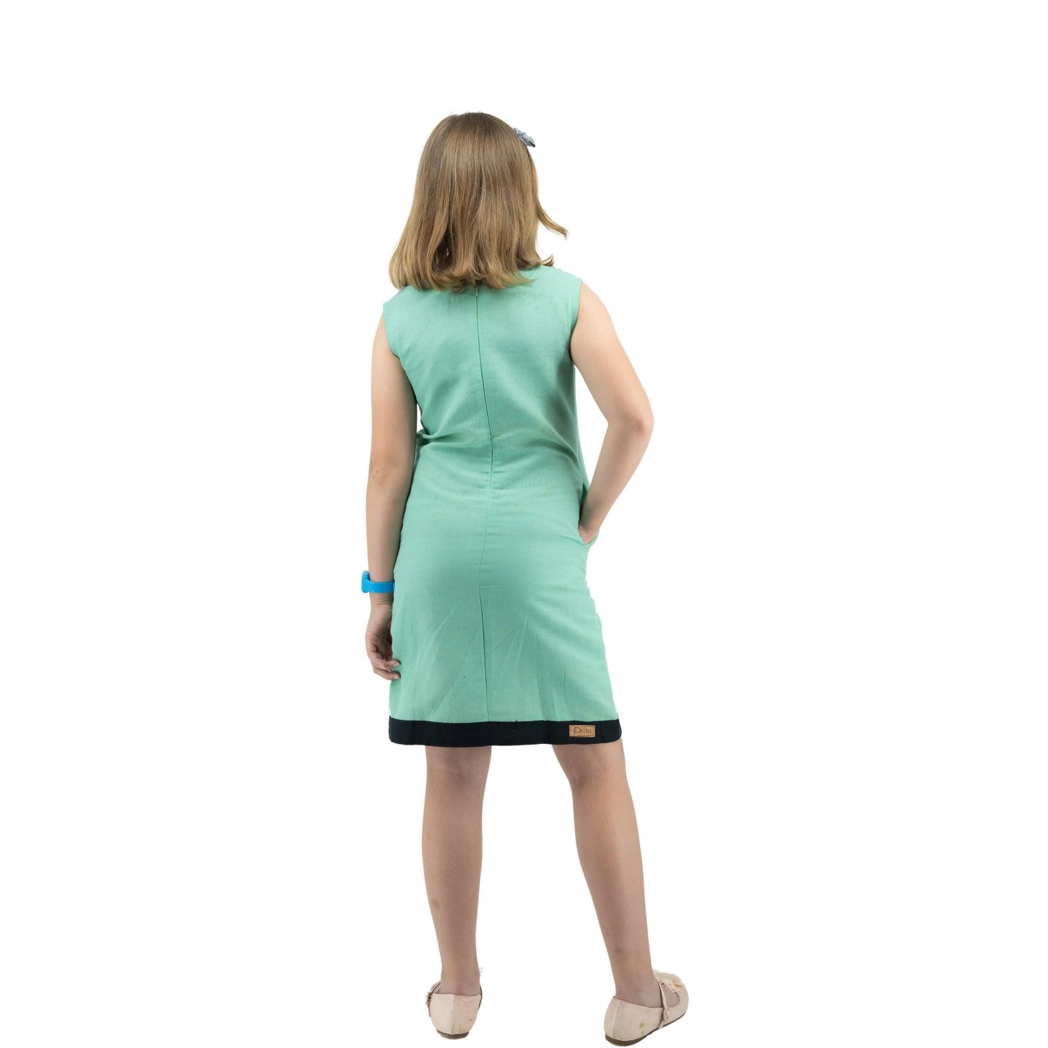 A woman in a Karee Neptune green Linen Cotton Round Neck Frock for Kids standing with her back to the camera against a white background.