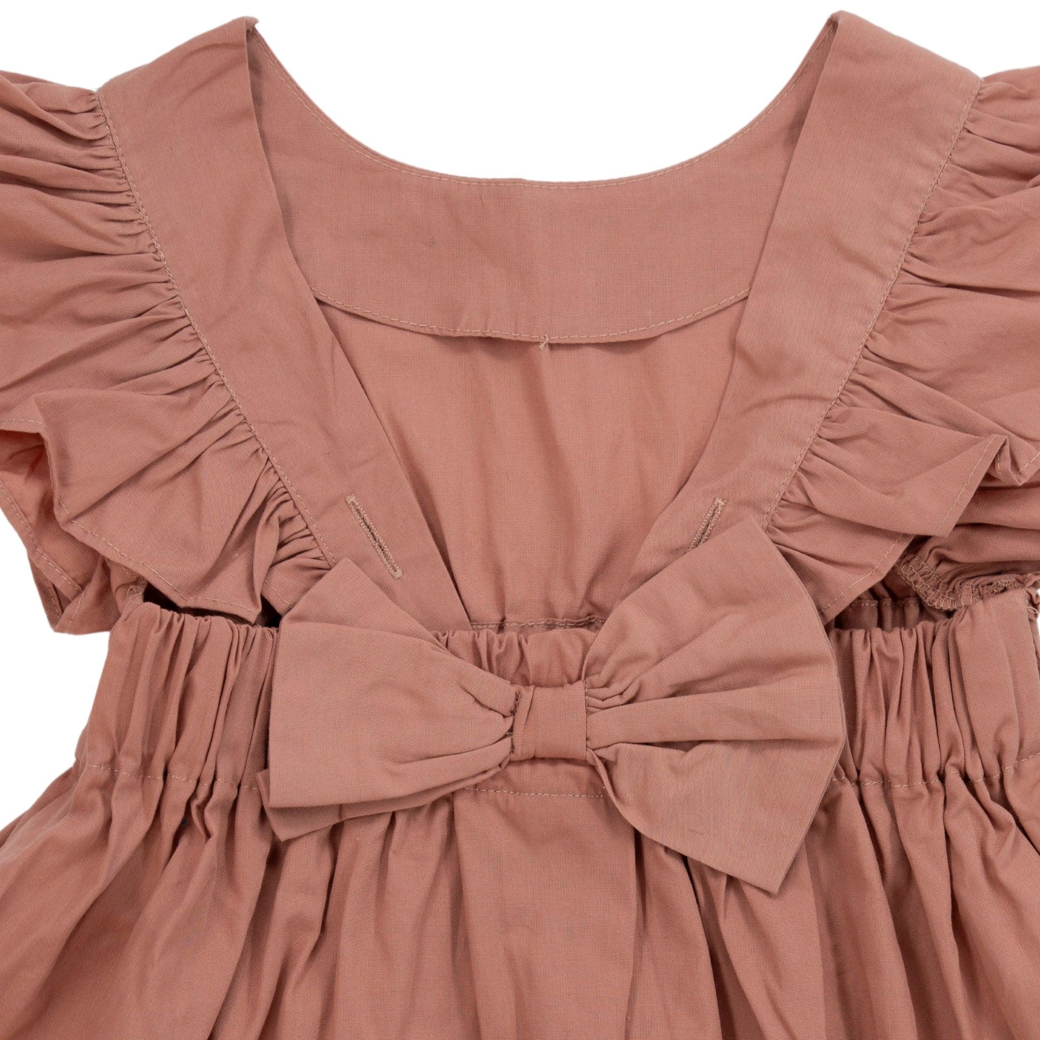 Close-up of a Brick Dust Cotton Floral Dress for Girls by Karee with ruffled sleeves and a bow detail at the waist against a white background.