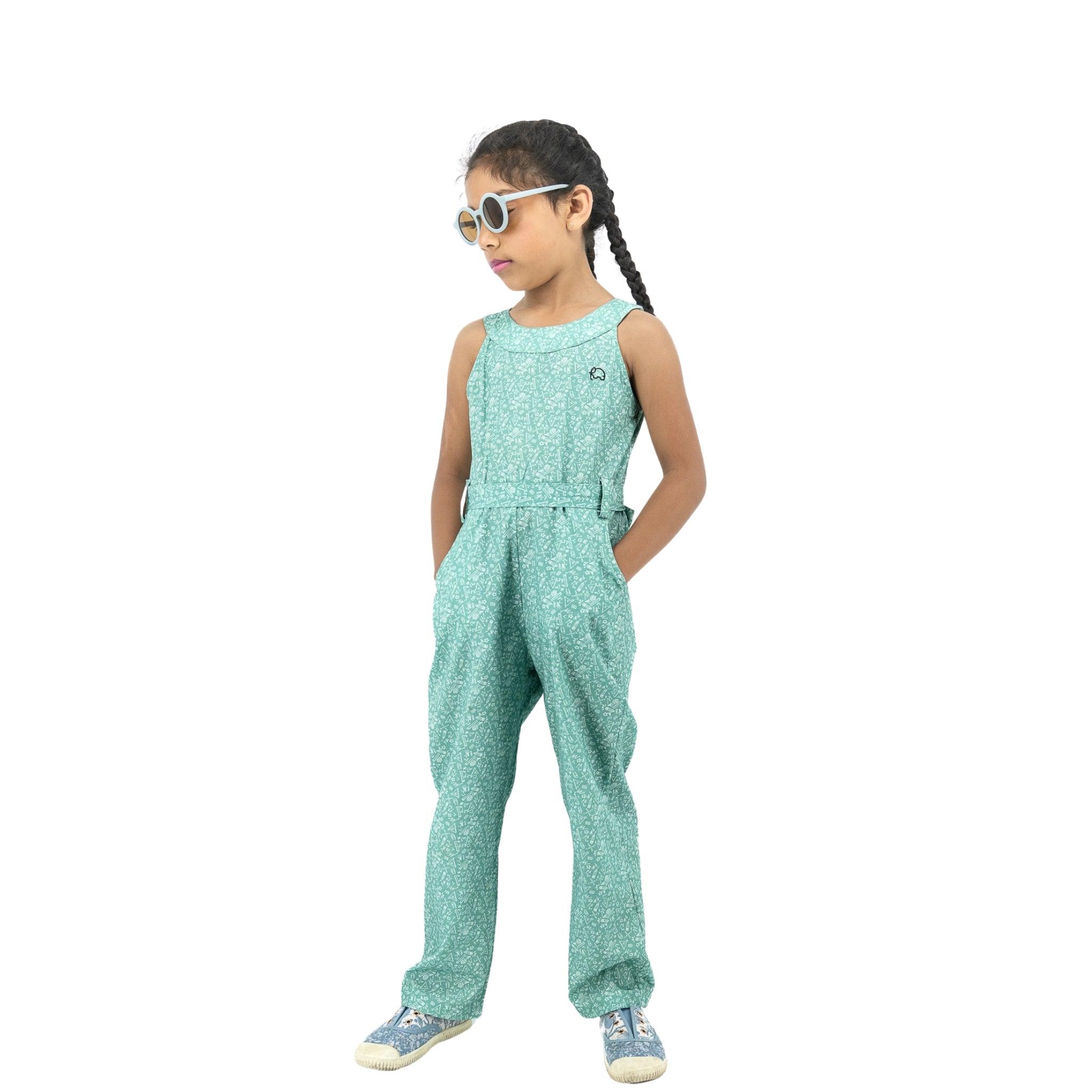 Young girl in a Karee Smoke Green Cotton Jumpsuit and sunglasses, standing with hands on hips against a white background.