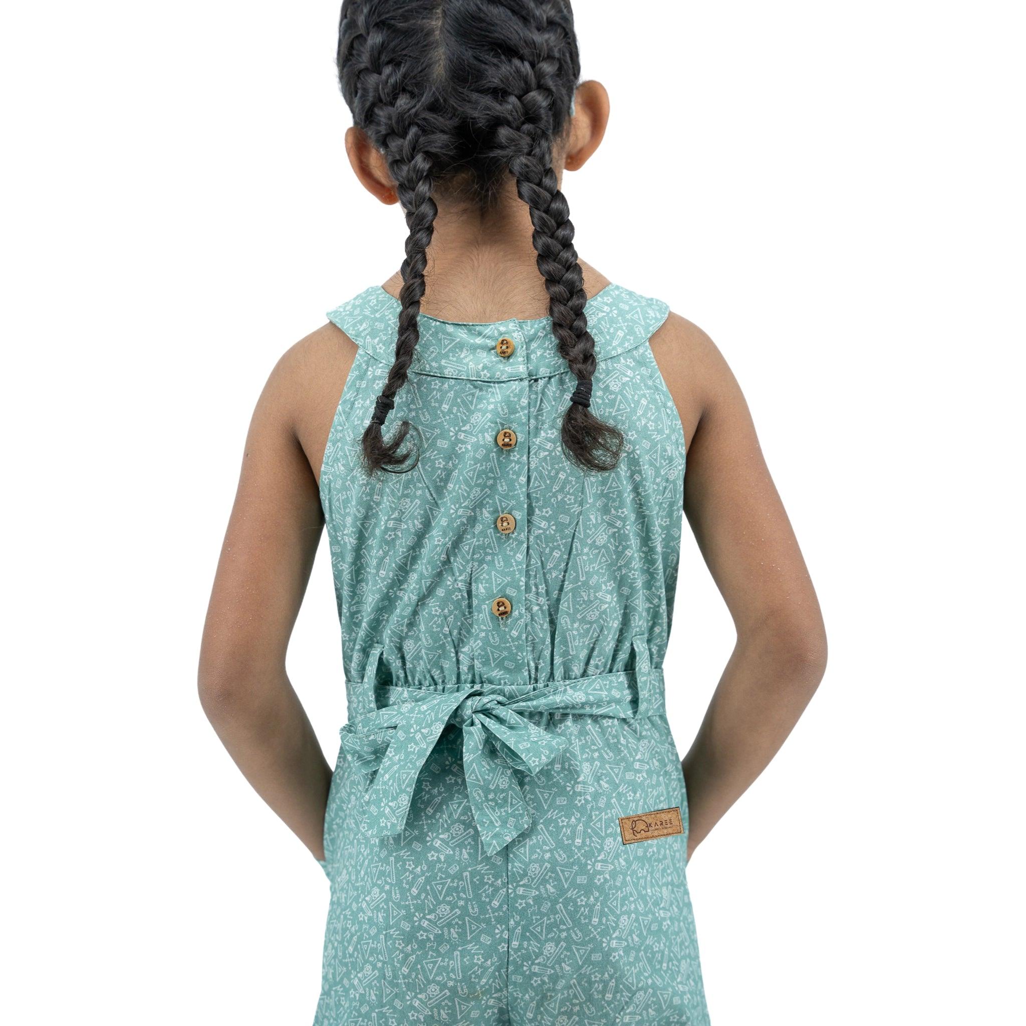 Young girl seen from behind, wearing a Karee Smoke Green Cotton Jumpsuit For Girls with a tied waist, featuring intricate braids in her hair.