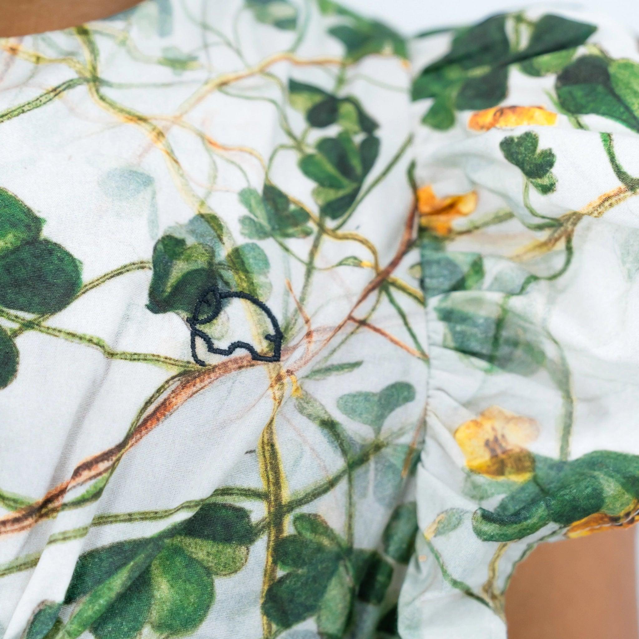 Close-up of a Karee Green Floral Cotton Dress for Girls with a detailed leaf and floral print in green and orange colors.