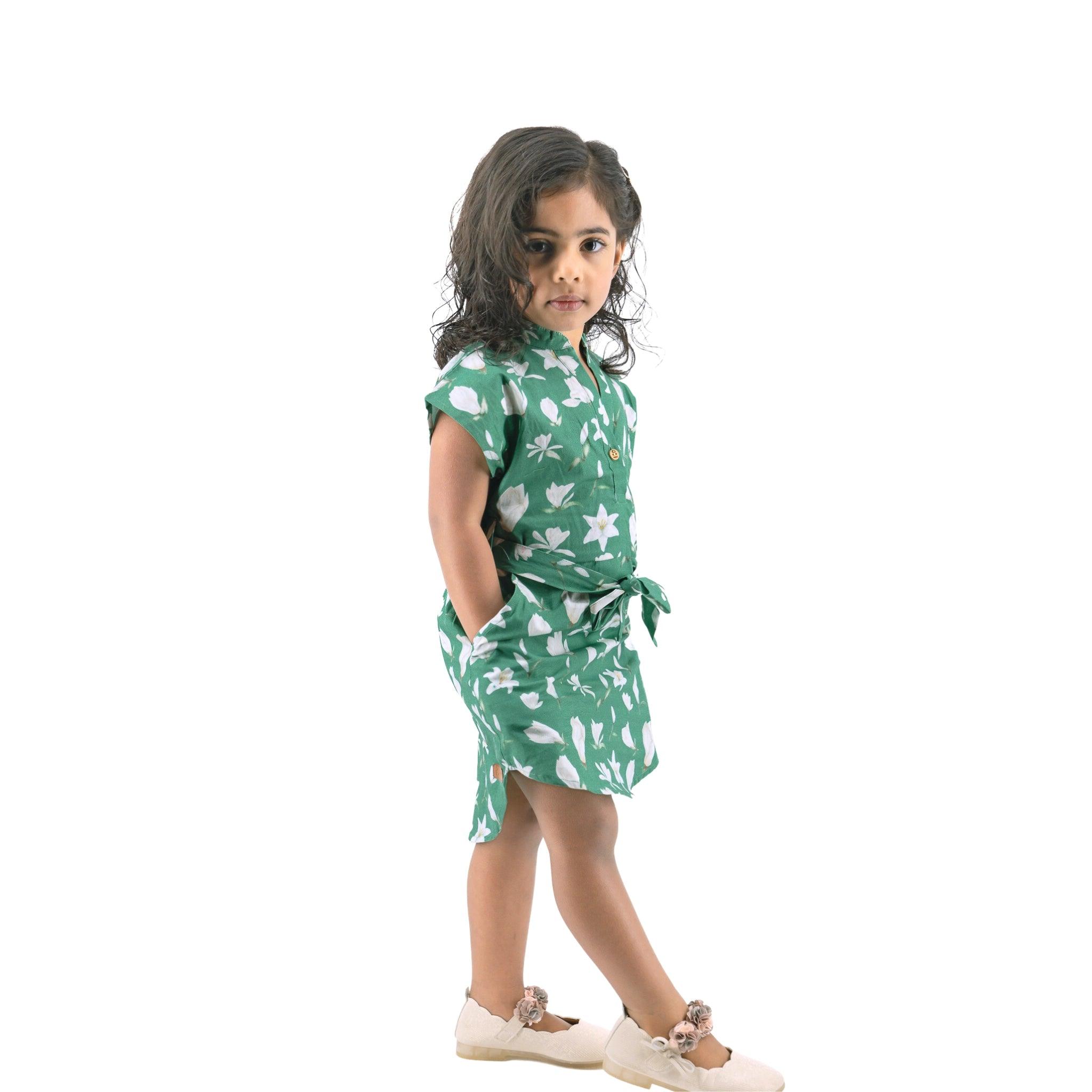 Young girl in a Bottle Green Lilly Blossom Cotton Shirt Dress for Kids by Karee looking back over her shoulder, standing against a white background.