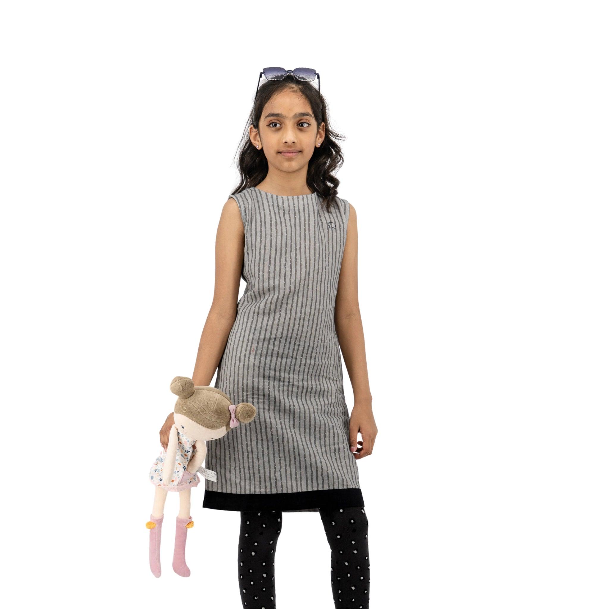 Young girl in a Karee Linen Cotton Round Neck Frock for Kids in Steel Grey holding a doll, standing against a white background.