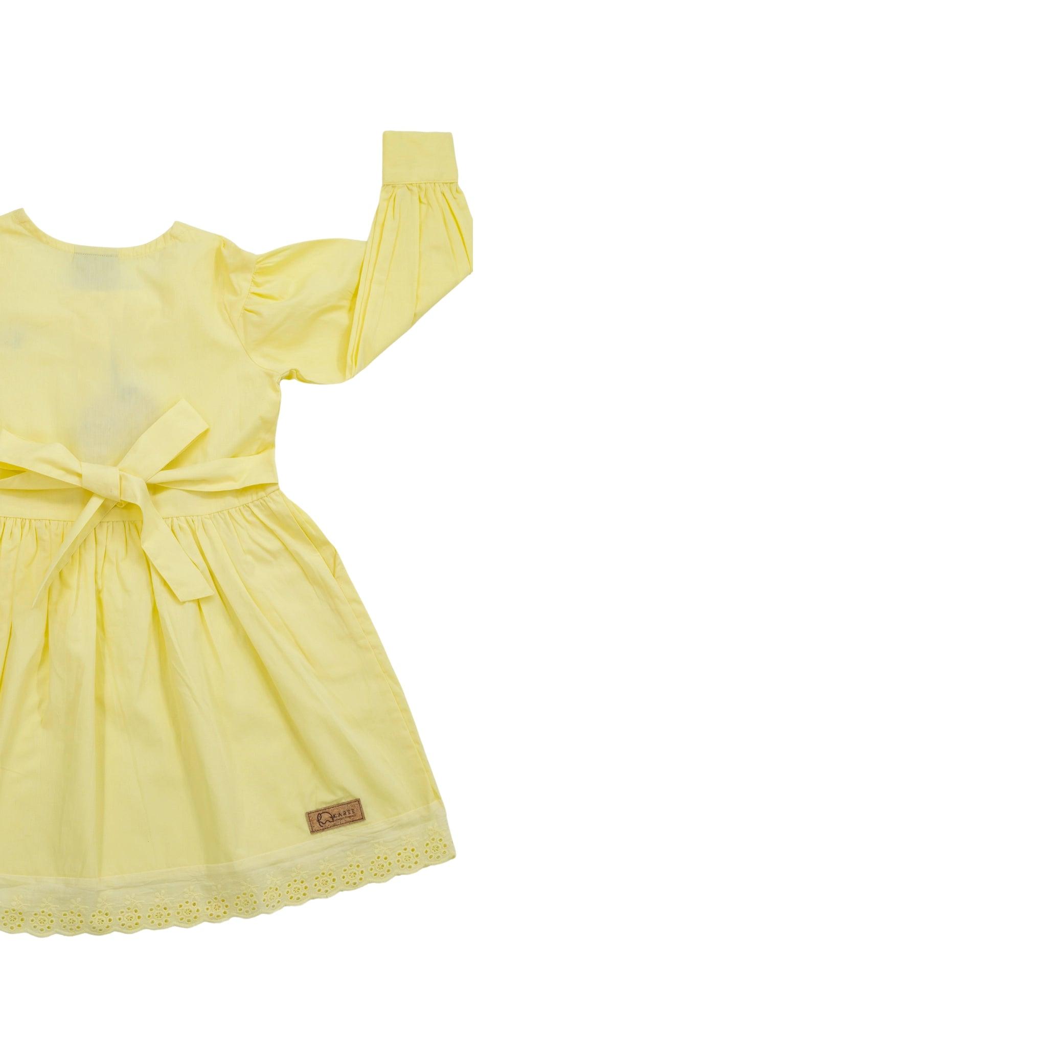 Yellow Karee children's dress with long puff sleeves, a bow at the back, and lace trim, isolated on a white background.