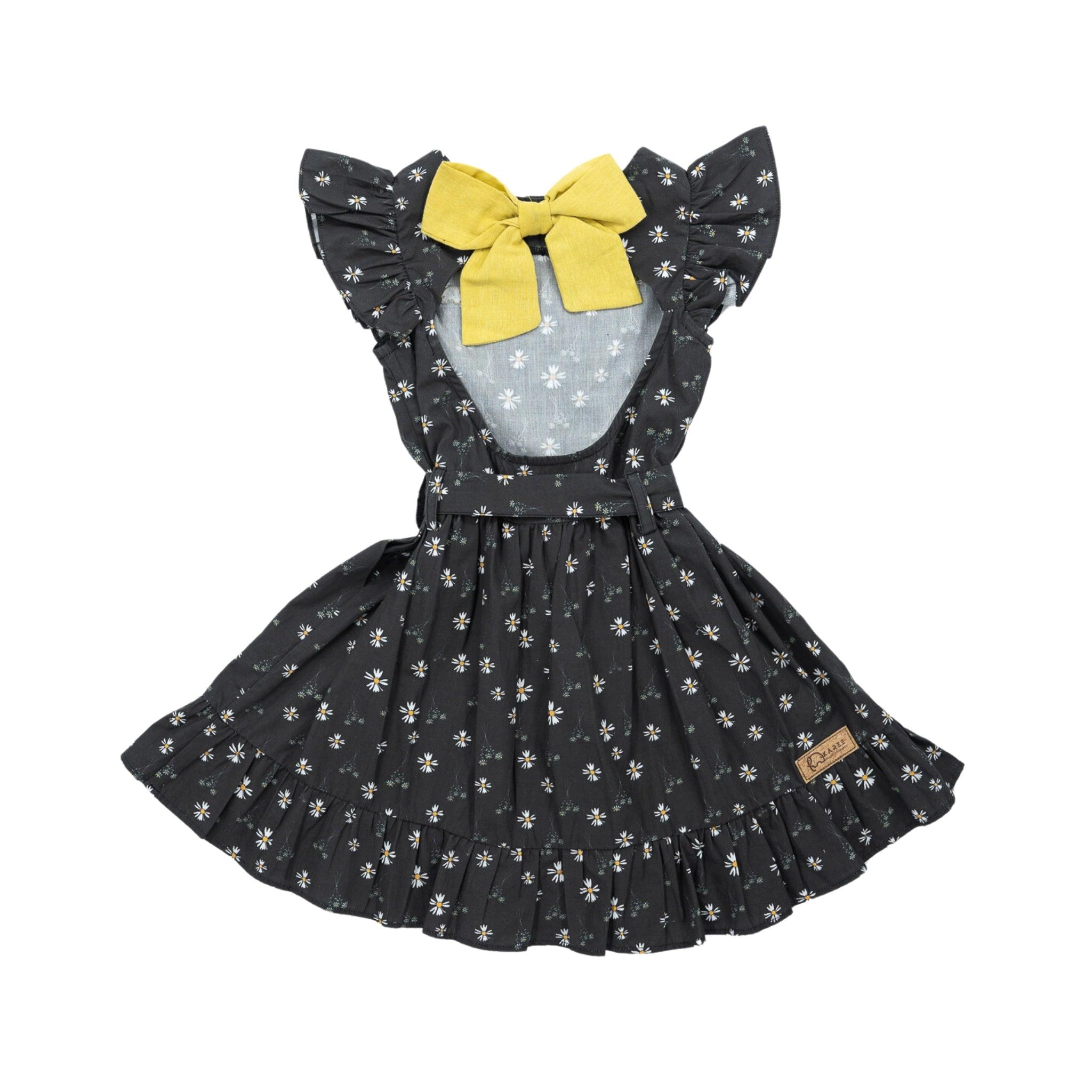 A Karee Petite Blossom Black Cotton Dress with a yellow bow, flutter sleeves, and a skirt flared for volume, displayed against a white background.