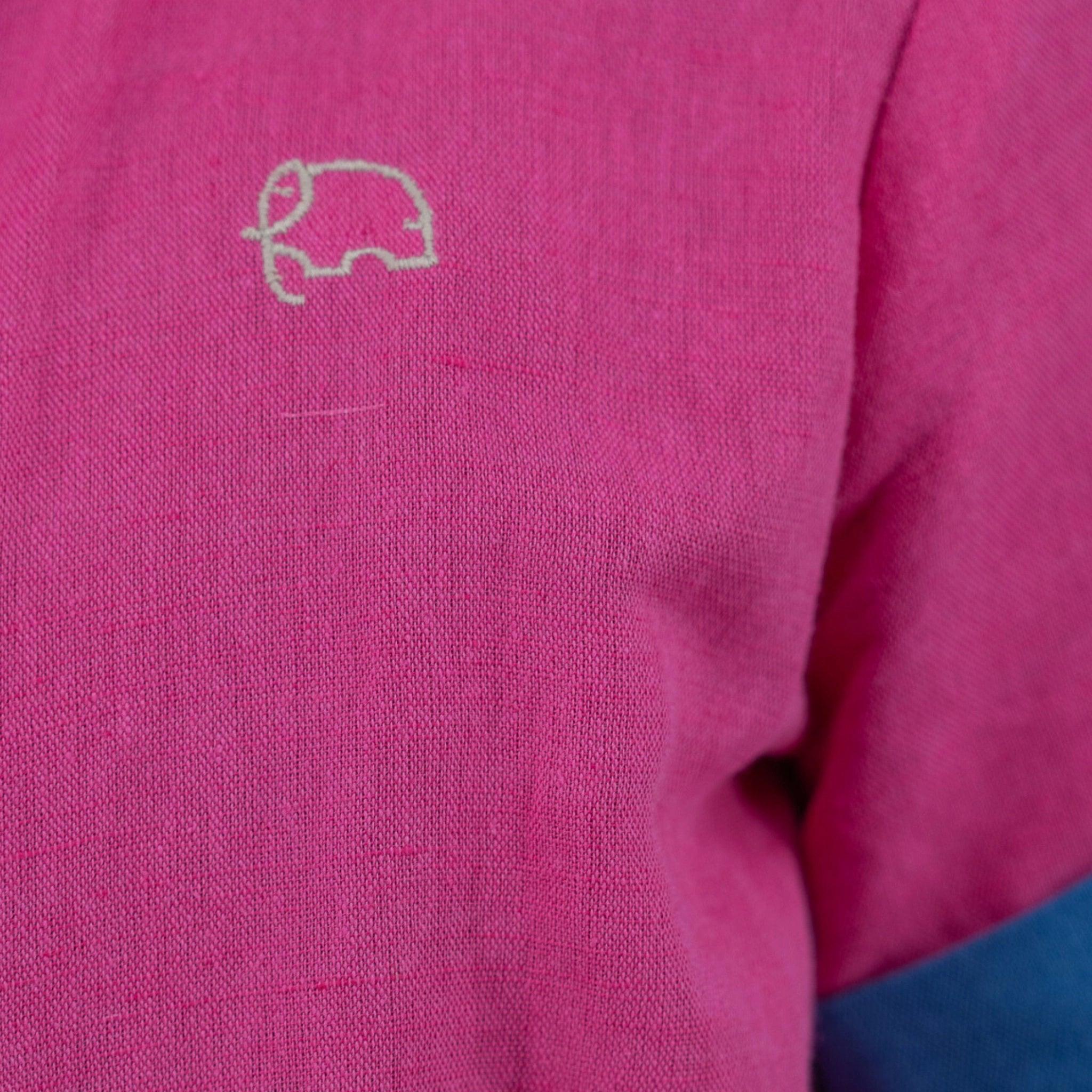 Close-up of a Karee fuchsia purple linen dress for girls with a small white embroidered logo resembling a car on the left chest area.
