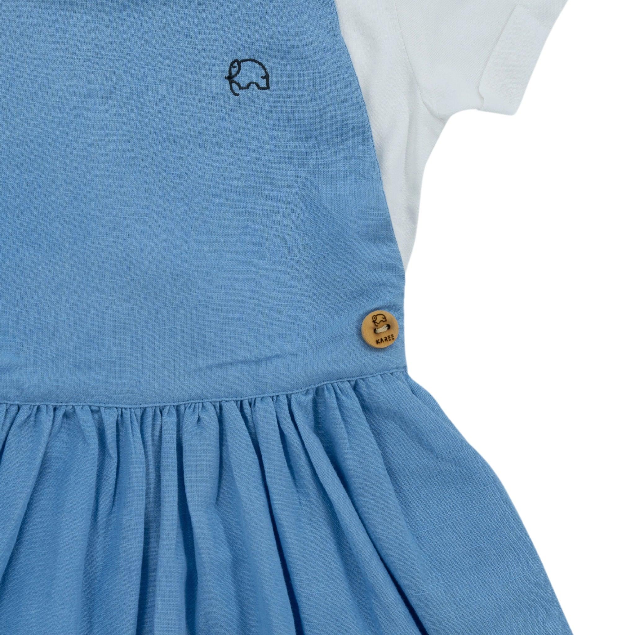 Cerulean Blue Linen girls' pinafore with a small elephant motif on the chest and a wood button on the side by Karee.