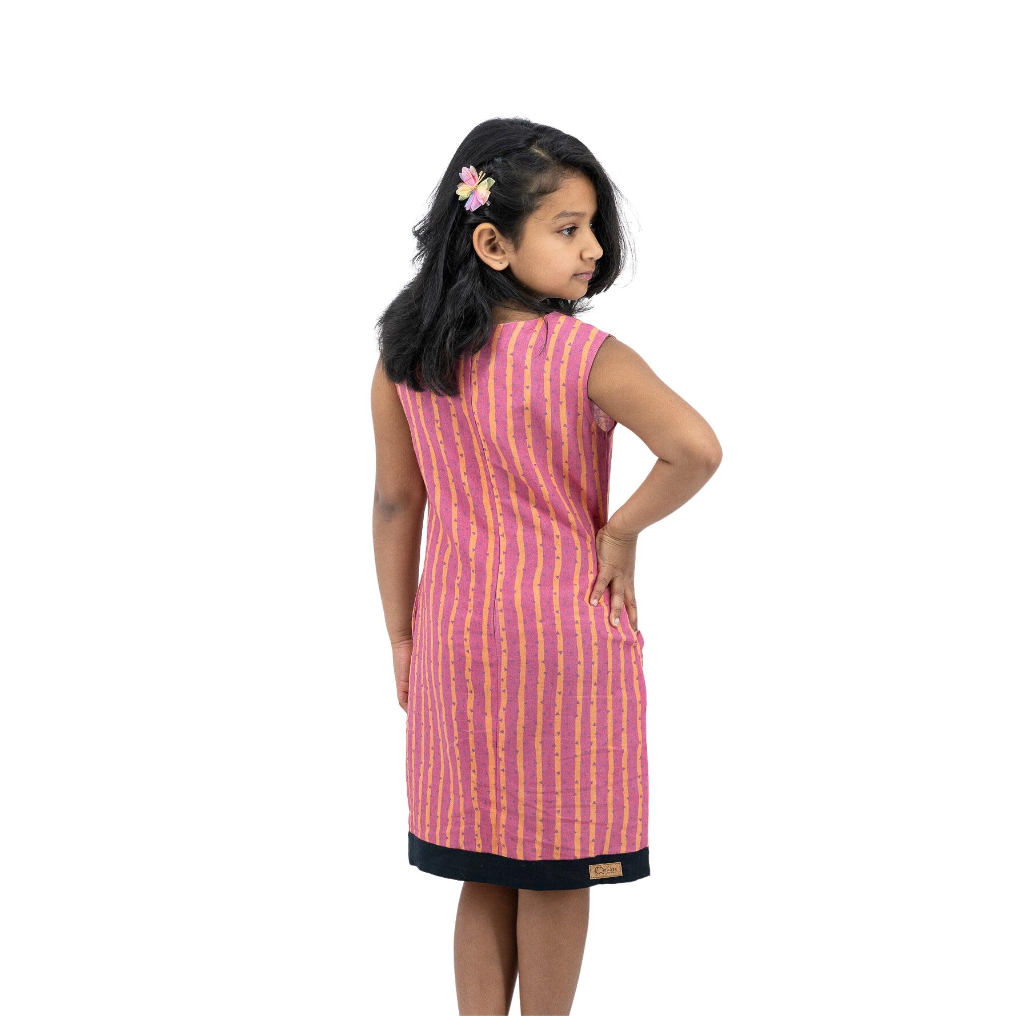 A girl in a Karee Linen Cotton Round Neck Frock for Kids in Lilac Rose with black stripes.