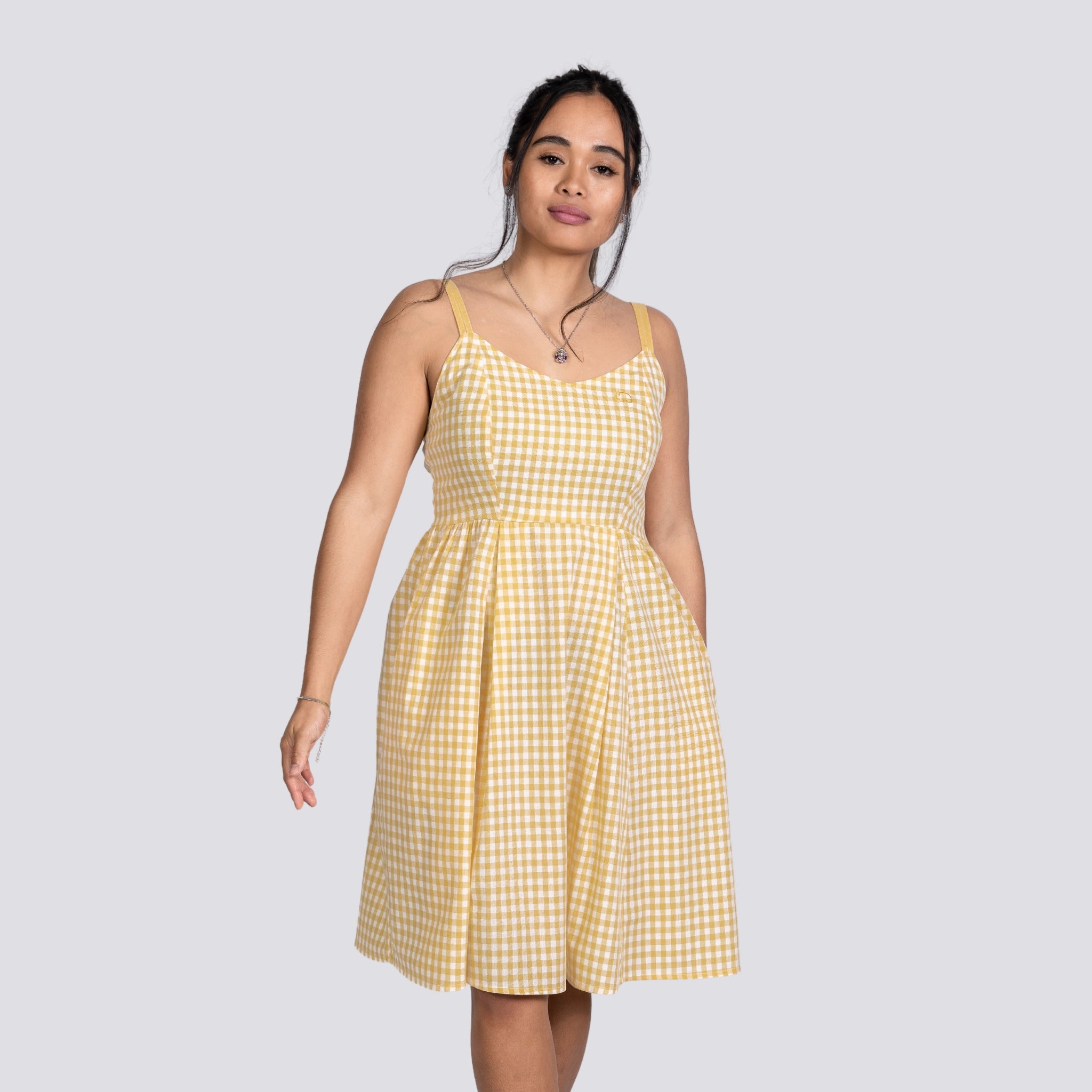 A young woman stands wearing a Karee Sunshine Chic Yellow Plaid Cotton Mini Dress, looking directly at the camera with a neutral expression.