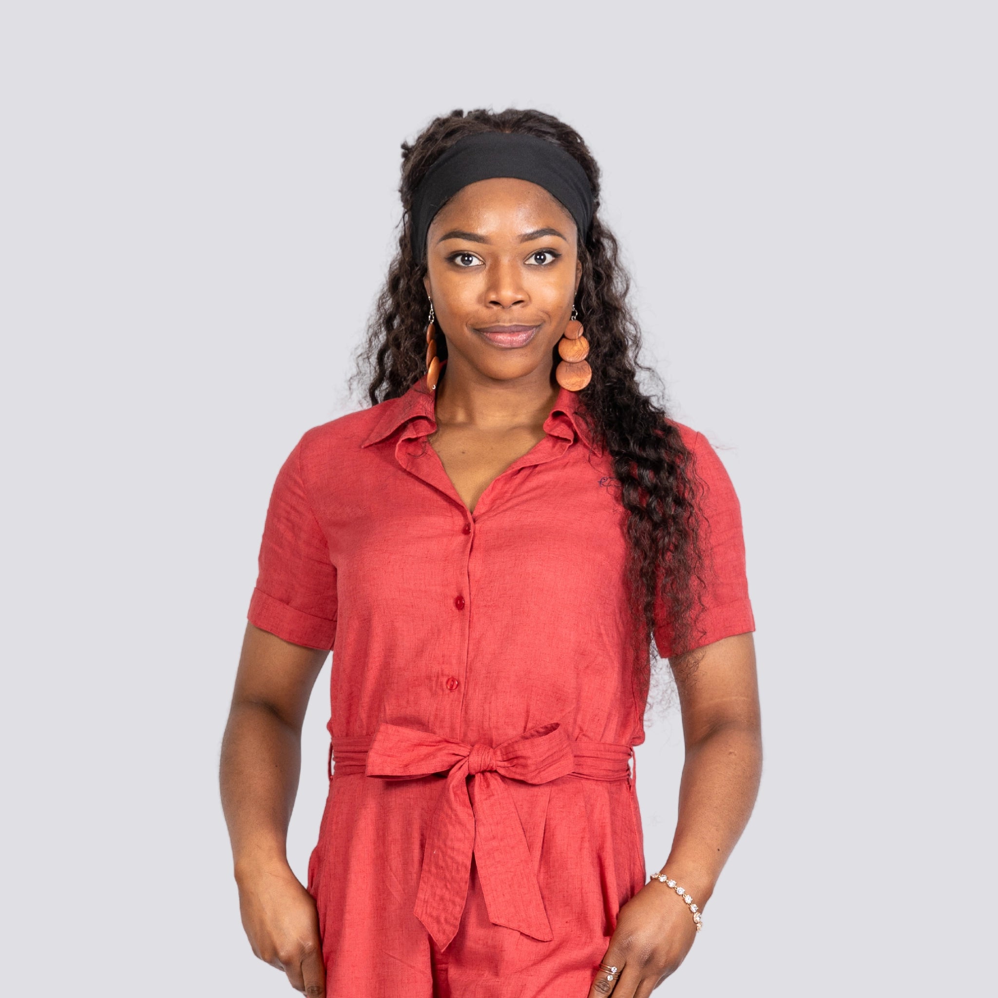 A woman wearing a Karee Milano Red Serenity Viscose Linen Jumpsuit and a headband stands facing the camera with a neutral expression.