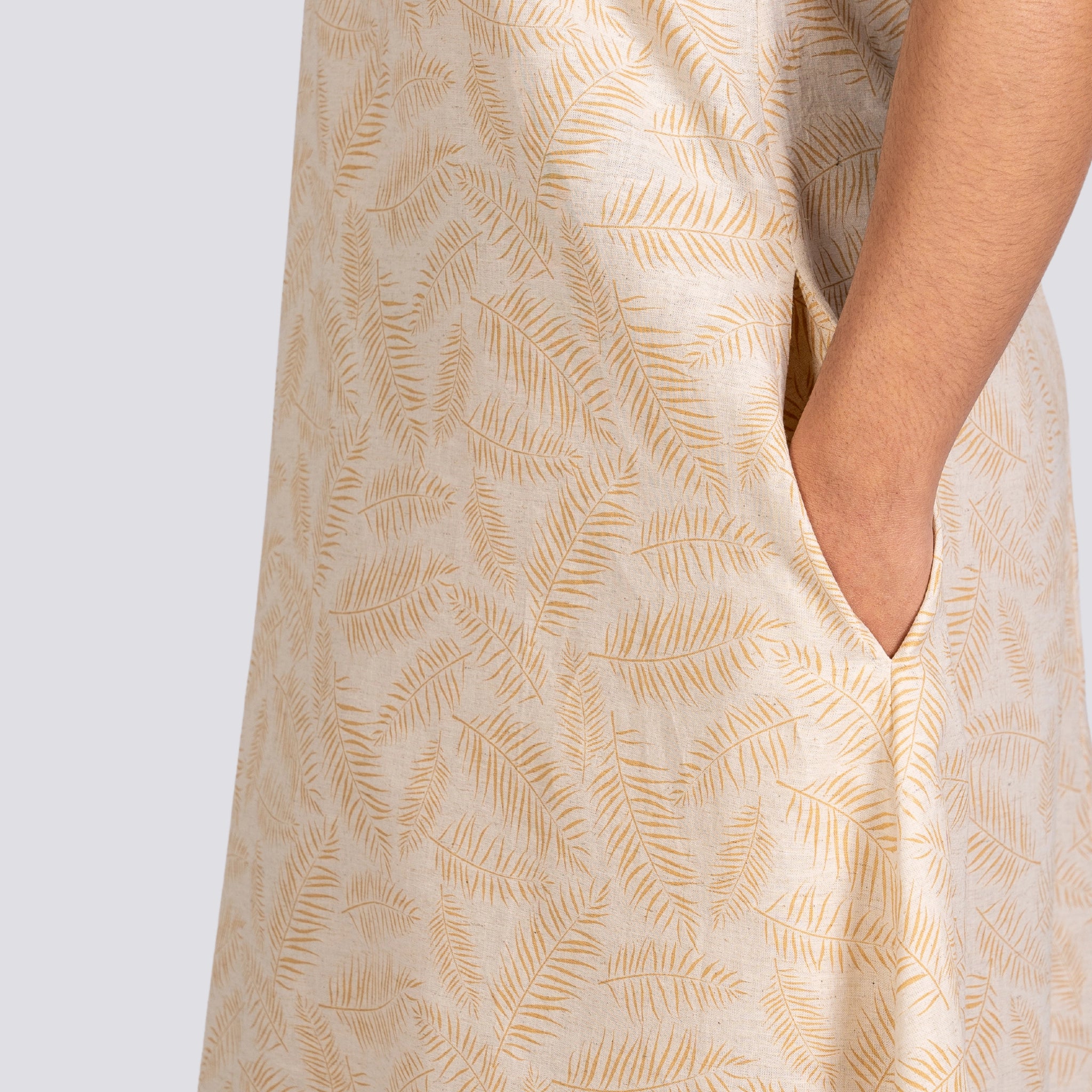 Close-up of a person wearing a beige dress with a Karee Mystic Serenity High Low Linen Cotton Midi Dress, focusing on the side seam and pocket detail.