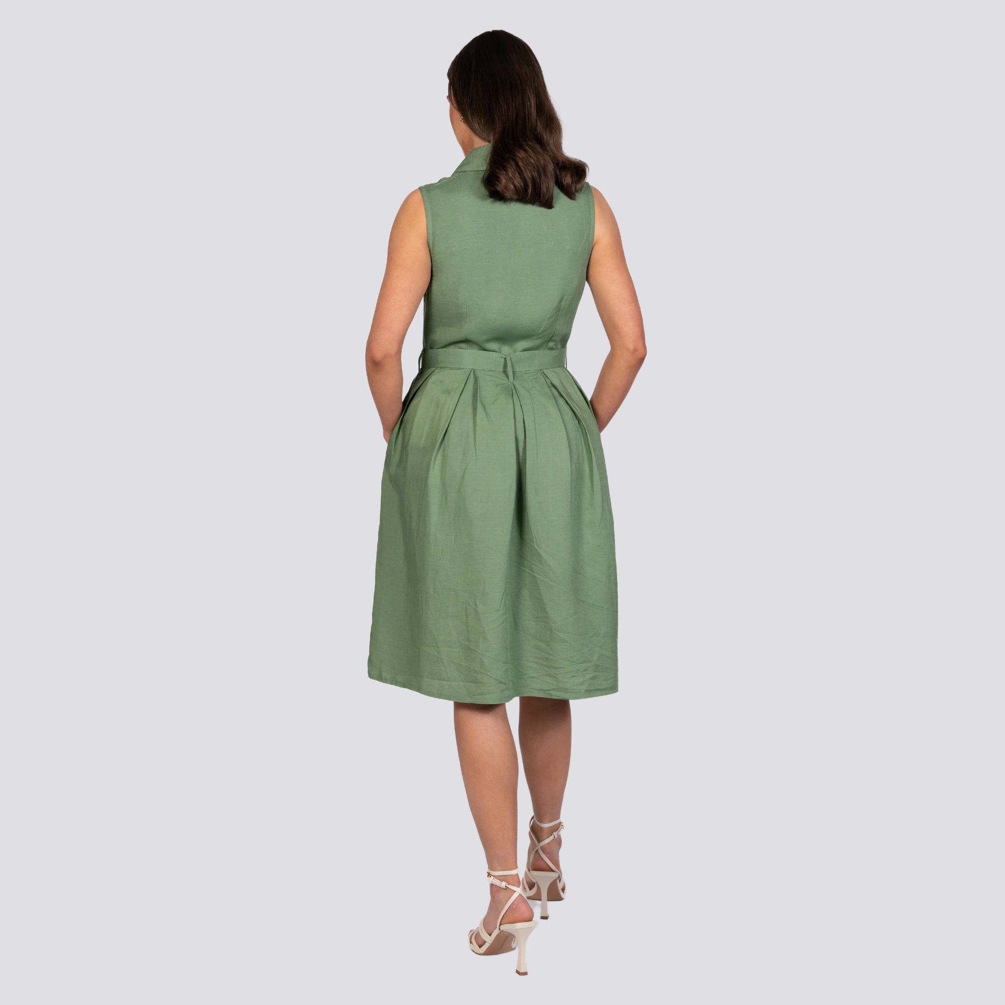 Woman standing with her back to the camera, wearing a Karee green Vintage Midi Button-Up Dress and cream strappy heels, against a plain background.