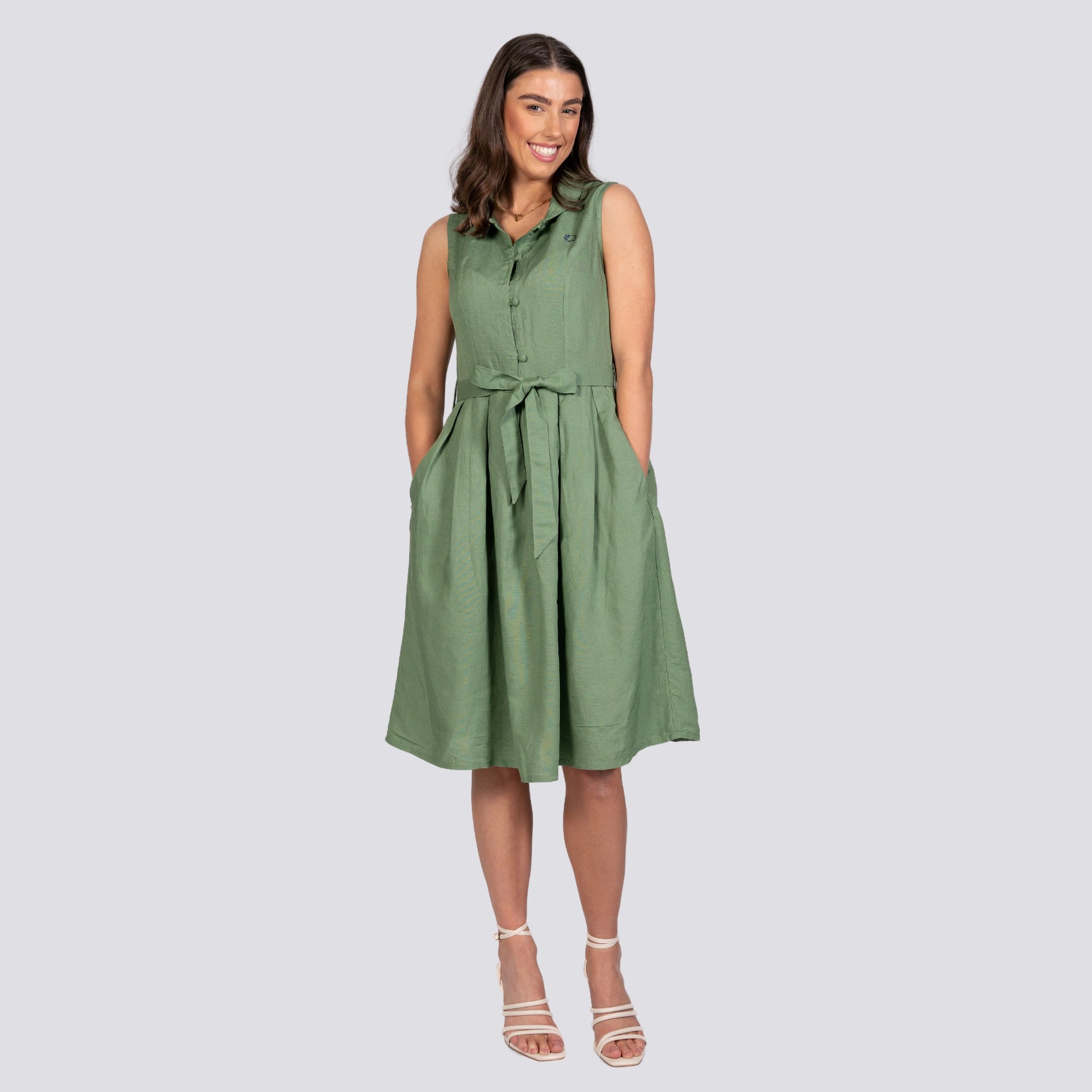 A smiling woman in a Karee green sleeveless Vintage Midi Button-Up Dress with a belted waist, standing against a plain background.