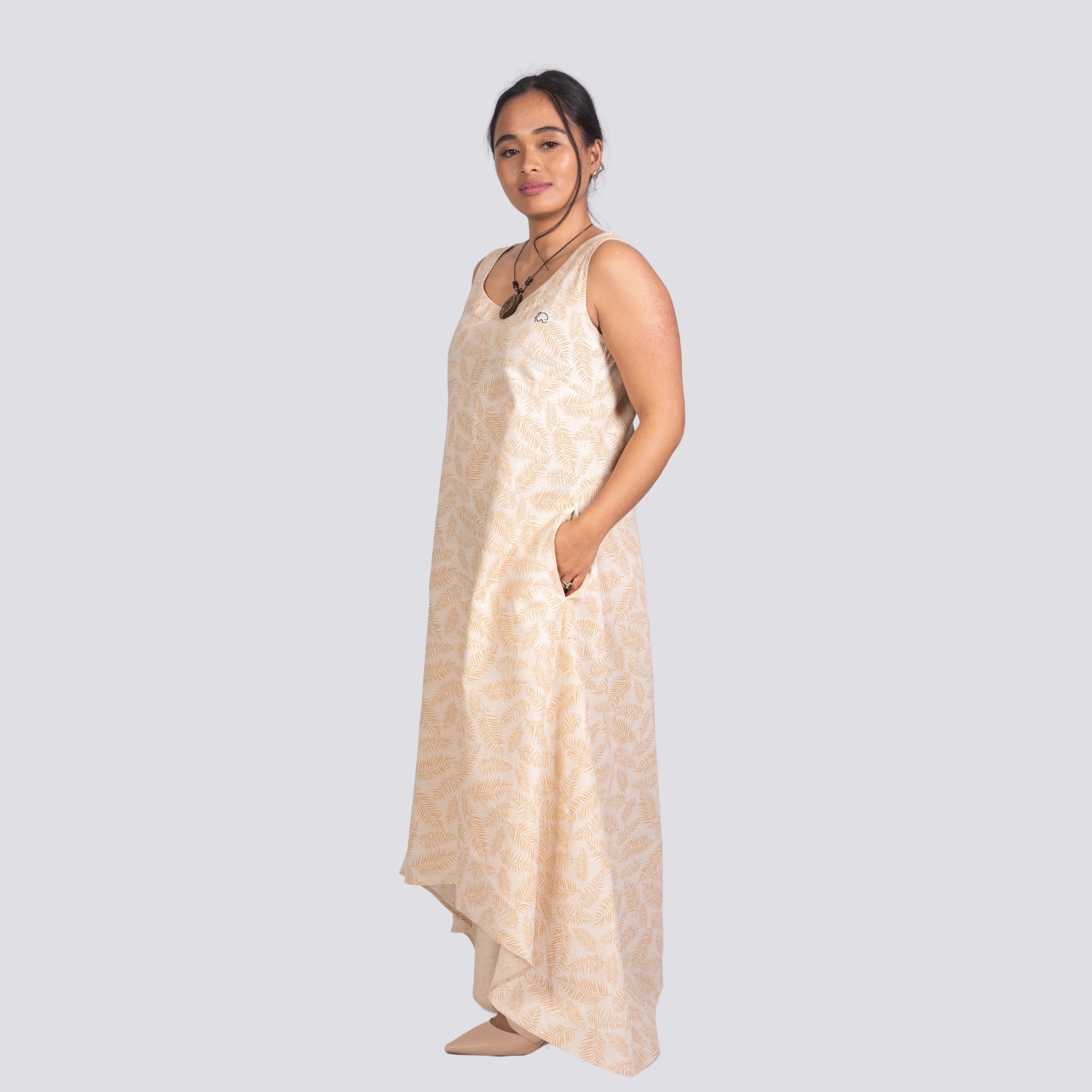 A woman in a sleeveless U-neck design Karee Mystic Serenity High Low Linen Cotton Midi Dress stands confidently, looking towards the camera, against a light gray background.
